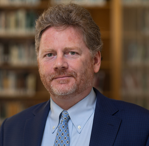 Russell Carey wearing a blue suit in a library