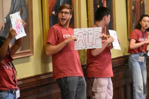 Students at the Global Brown Center excitedly hold up signs at a community event