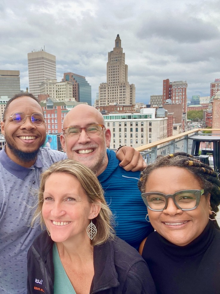 Four Residential Life directors smile with the city skyline behind them
