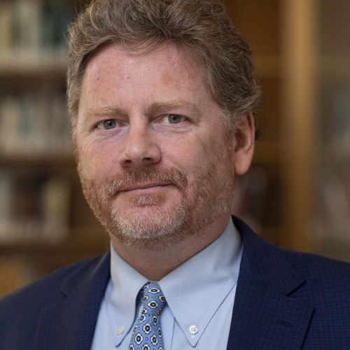 Russell Carey in a dark suit in a library